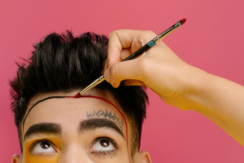 a man that has some paint on his face, an album cover, by Julia Pishtar, trending on pexels, hyperrealism, holding pencil, flat top haircut, asian human, head straight down