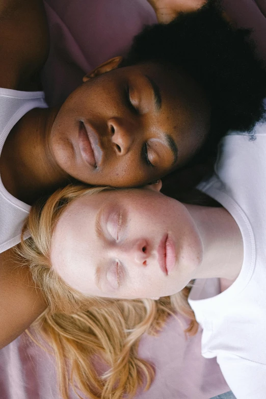 a couple of women laying on top of a bed, inspired by Nan Goldin, trending on pexels, renaissance, mixed-race woman, a blond, beautiful highly symmetric faces, close-up portrait film still