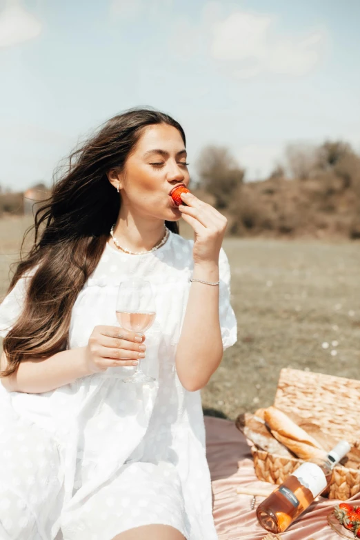 a woman sitting on a blanket eating a piece of food, wearing a white dress, woman with rose tinted glasses, 🍸🍋, profile image