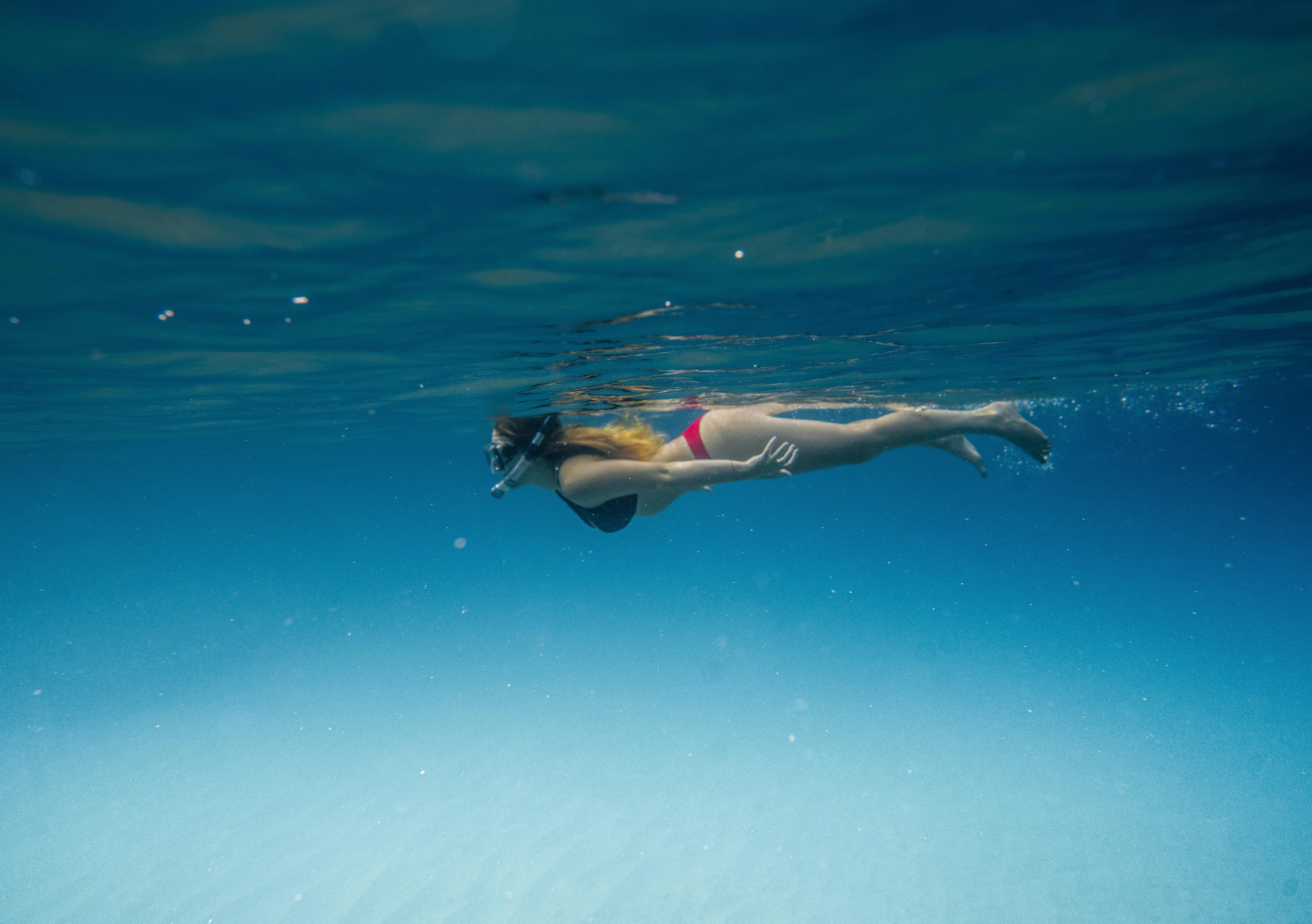 a woman in a bikini swims under water, unsplash contest winner, blue sky, fan favorite, shot with sony alpha, worried