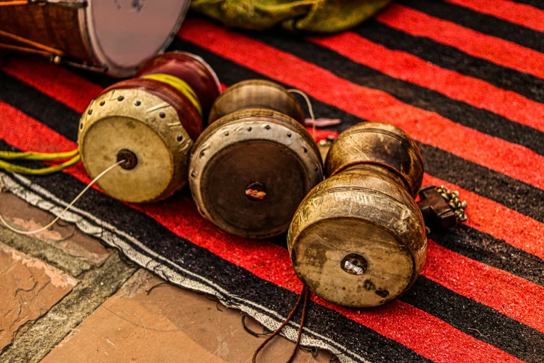 a group of drums sitting on top of a red and black rug, by Julia Pishtar, hurufiyya, bells, marrakech, thumbnail, a wooden