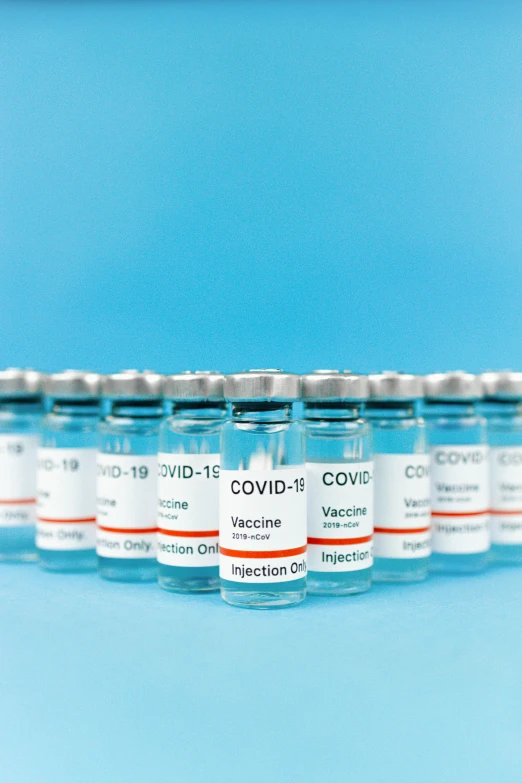 a row of vials filled with vaccines on a blue background, instagram post, featured, covid, grey