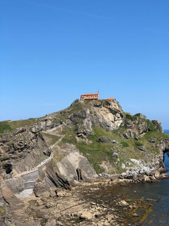 a small island in the middle of a body of water, rock roof, spanish, standing on a cliffside, 400 steps