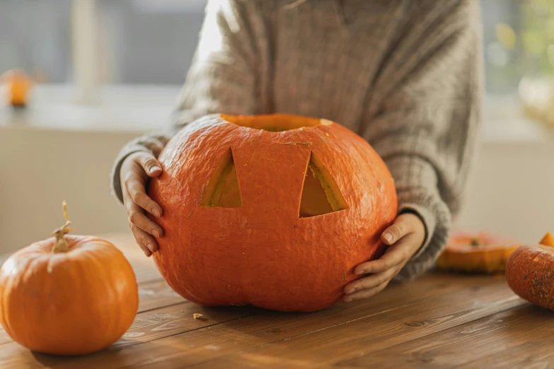 a woman holding a pumpkin on top of a wooden table, inspired by Sarah Lucas, trending on pexels, made of lab tissue, jack - o'- lantern, handcrafted, press shot