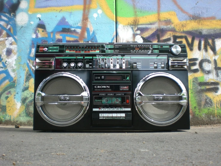 a boombox sitting in front of a graffiti covered wall, crown, promo image, triple six, radio equipment