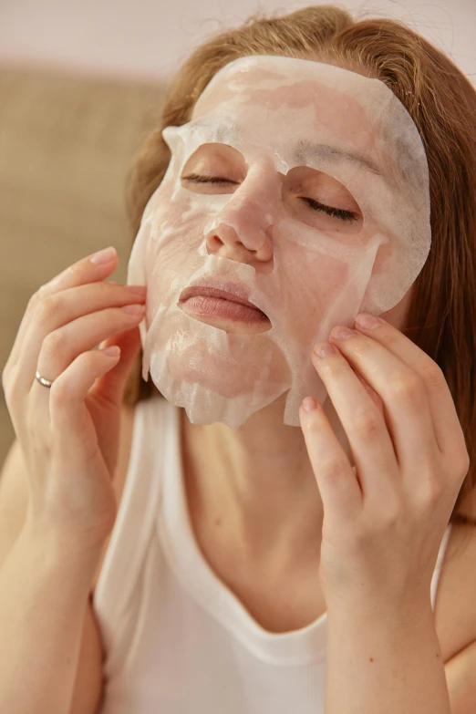 a woman is shaving her face with a facial mask, by Julia Pishtar, wearing translucent sheet, gooey skin, some of them use gask mask, sleepy