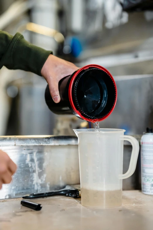 a person pouring something into a cup on a counter, process art, silo, thumbnail, environmental, beer