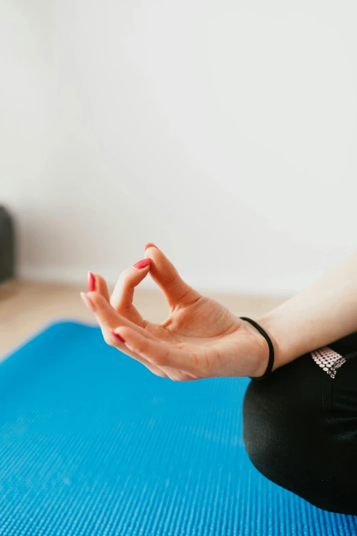 a woman sitting on a yoga mat with her hands in the air, trending on pexels, visual art, square, point finger with ring on it, low quality photo, thoughtful