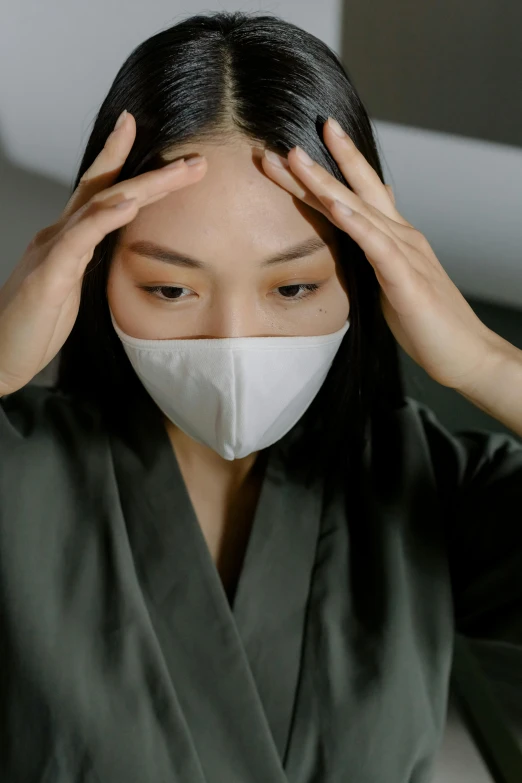 a woman with a mask covering her face, inspired by Yu Zhiding, trending on pexels, wearing lab coat and a blouse, exhausted, asian face, wearing a grey robe