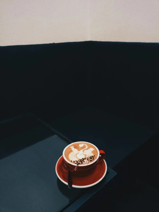 a cup of coffee sitting on top of a table, inspired by Elsa Bleda, profile image, dark orange black white red, trending on vsco, cappuccino