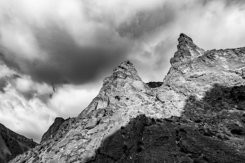 a black and white photo of a mountain, a black and white photo, unsplash, figuration libre, asymmetrical spires, dramatic sky, limestone, low angle 8k hd nature photo