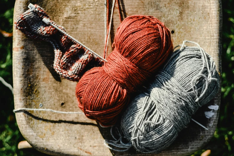 two balls of yarn sitting on top of a chair, a portrait, unsplash, red brown and grey color scheme, having fun in the sun, promo image, ignant