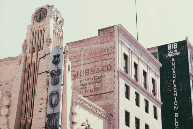 a tall building with a clock on top of it, a colorized photo, inspired by Edward Ruscha, pexels contest winner, old signs, sunfaded, post apocalyptic san francisco, buildings carved out of stone