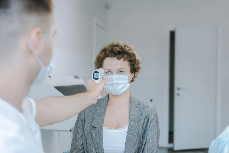 a man putting a mask on a woman's face, a colorized photo, by Adam Marczyński, pexels contest winner, thermography, people at work, with a stethoscope, brown