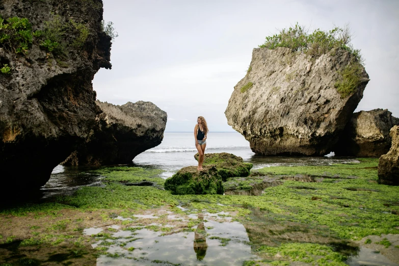 a woman standing on a rock in front of a body of water, a picture, bali, avatar image