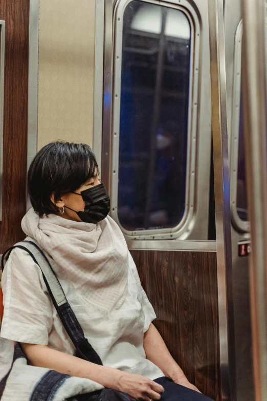 a woman wearing a face mask sitting on a subway, happening, slide show, multiple stories, us, trauma