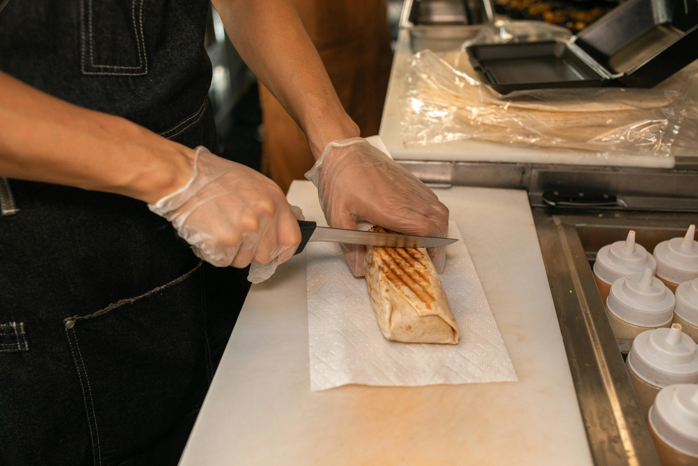 a person cutting a sandwich on a cutting board, a marble sculpture, by Tom Bonson, pexels contest winner, aussie baristas, cloth wraps, parchment, grilled chicken