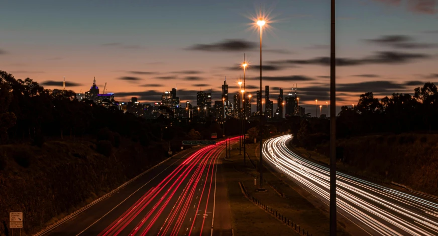 a city street filled with lots of traffic at night, by Lee Loughridge, unsplash contest winner, visual art, north melbourne street, highway and sunset!!, electrical signals, late morning