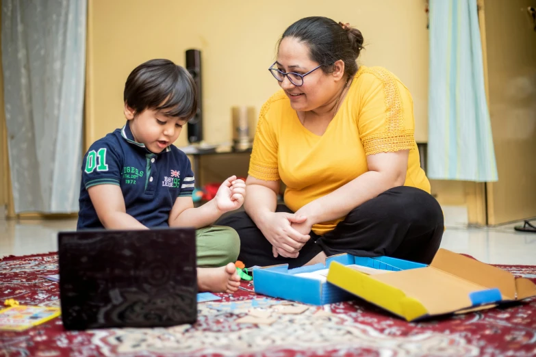 a woman sitting on the floor with a child, pexels contest winner, hurufiyya, from reading to playing games, delivering parsel box, te pae, school curriculum expert
