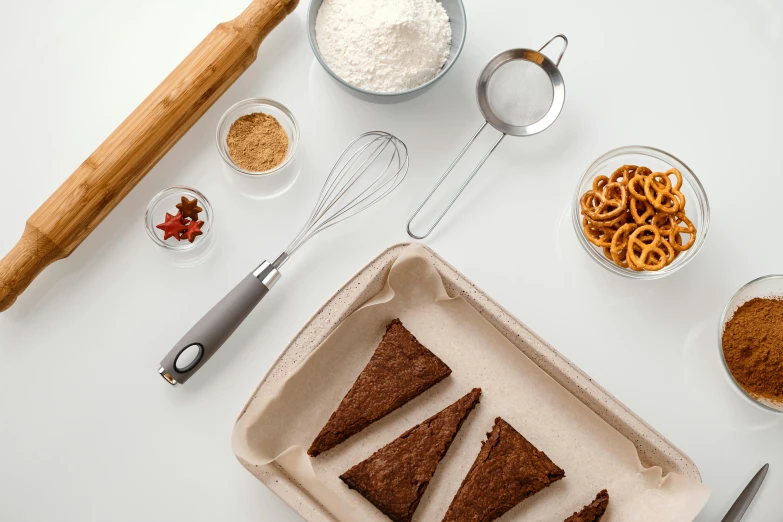 a tray of brownies sitting on top of a table, a still life, trending on pexels, metal kitchen utensils, triangular elements, thumbnail, set against a white background