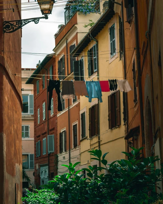 a narrow alley with clothes hanging out to dry, a colorized photo, pexels contest winner, renaissance, terracotta, view from the street, lgbtq, roman architecture