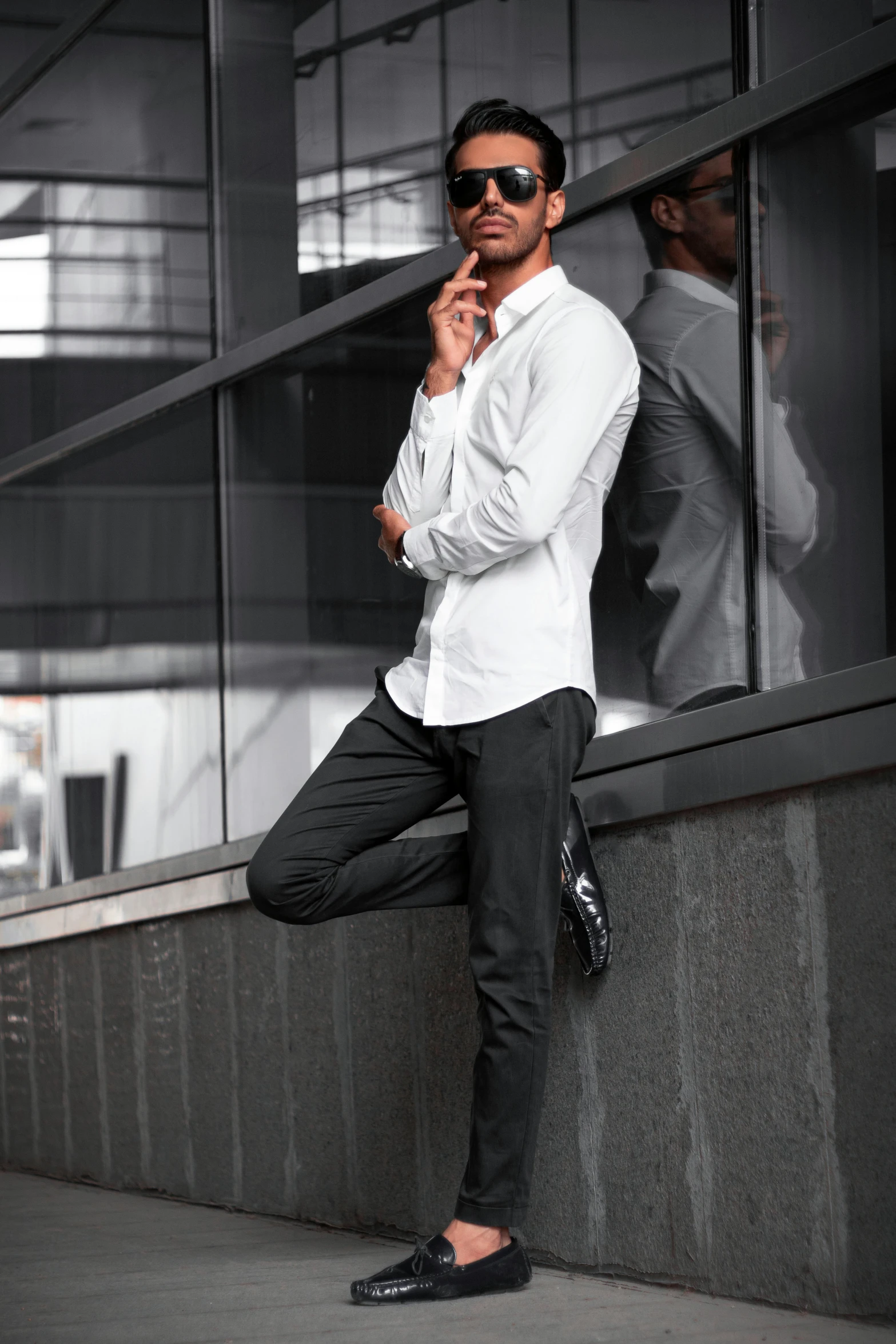 a man leaning against a wall talking on a cell phone, inspired by Henry Heerup, pexels contest winner, white dress shirt, matte black pants, full body with dynamic pose, [ cinematic