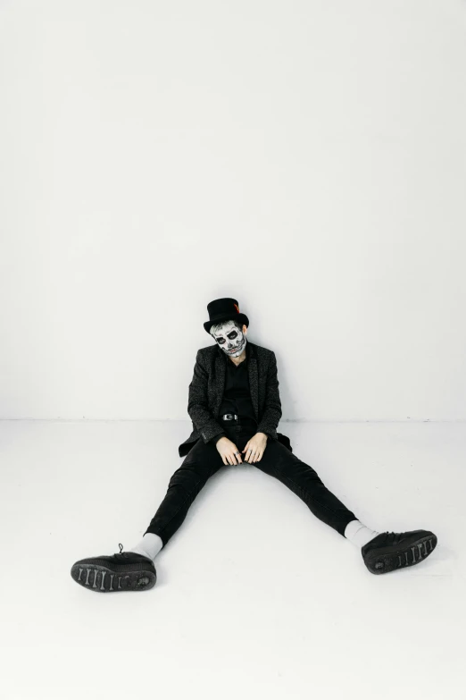 a man sitting on the floor in a white room, inspired by Taro Yamamoto, pexels contest winner, neo-dada, skull clown, black hat, declan mckenna, wide full body