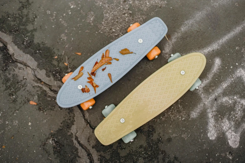 a couple of skateboards sitting next to each other, light grey blue and golden, birdseye view, grey orange, cream