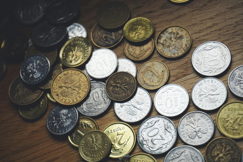 a pile of coins sitting on top of a wooden table, a screenshot, pexels contest winner, vintage inspired, new zealand, collection product, middle close up