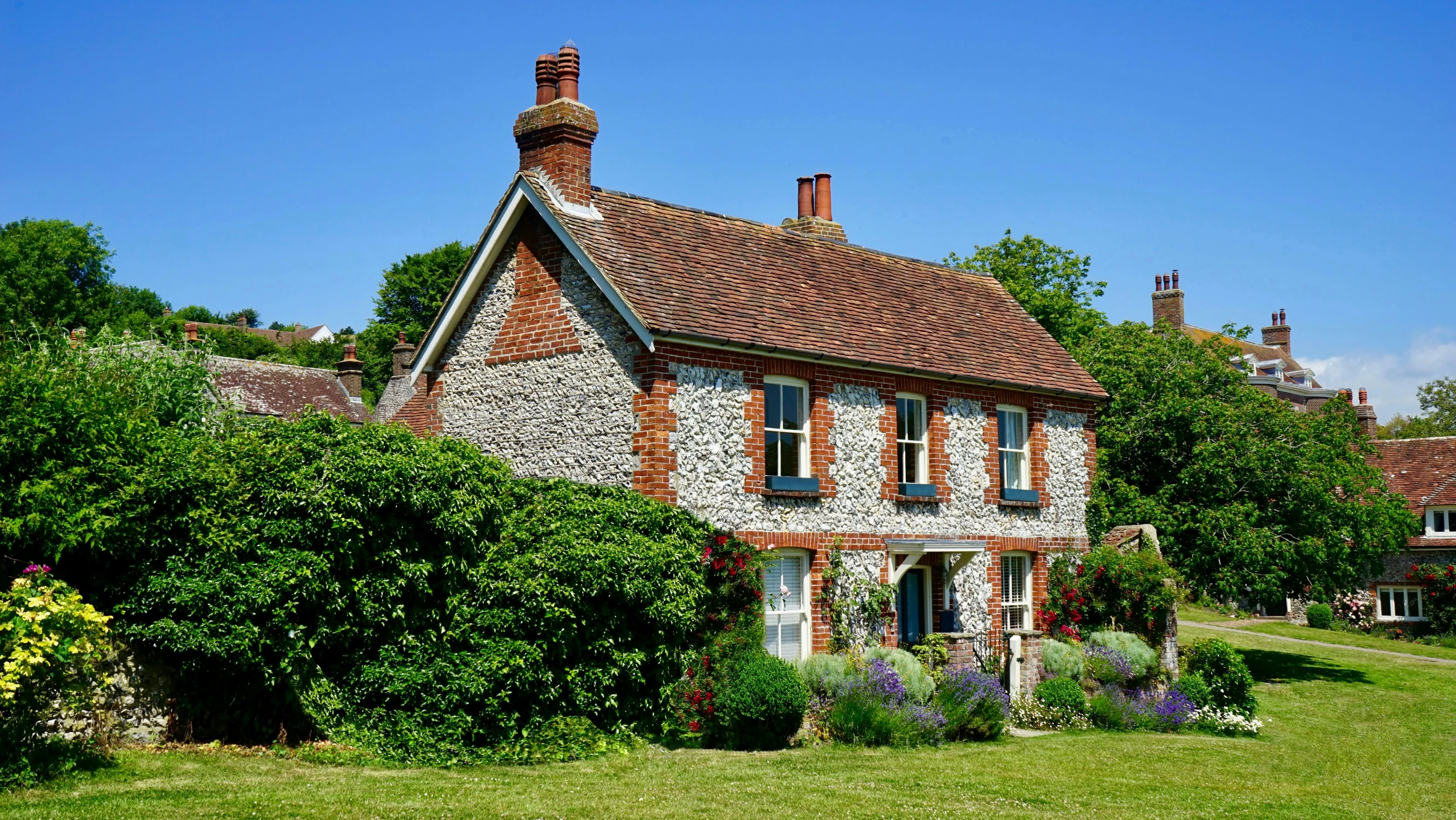 a house sitting in the middle of a lush green field, inspired by Eleanor Fortescue-Brickdale, exterior shot, grey, indigo and venetian red, preserved historical