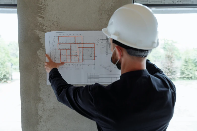 a man in a hard hat pointing at a blueprint, pexels contest winner, 15081959 21121991 01012000 4k, instagram post, concrete walls, no logo