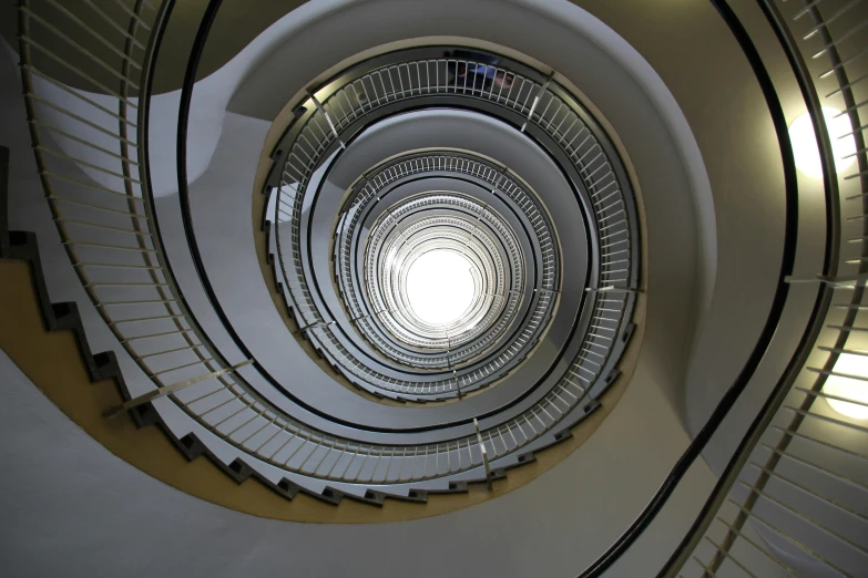 a spiral staircase with a light at the end, inspired by Alexander Rodchenko, pexels contest winner, bauhaus, worm\'s eye view, helsinki, circular towers, eyelevel perspective image