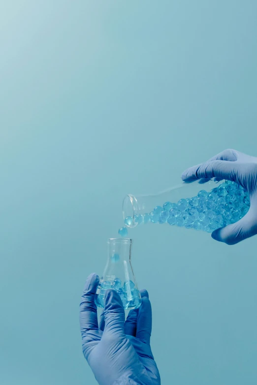 a close up of a person holding a bottle of liquid, analytical art, blue gloves, blue crystals, getty images, molecular