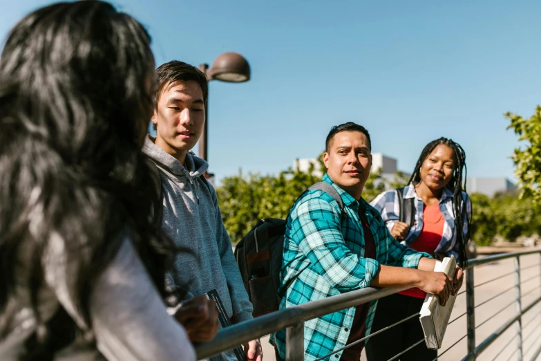 a group of people standing next to each other, a portrait, unsplash, happening, bay area, teaching, on a bridge, looking to his left