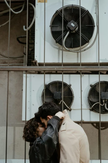 a couple standing next to each other in front of a building, a photo, trending on pexels, air conditioner, kissing together, industrial aesthetic, a high angle shot
