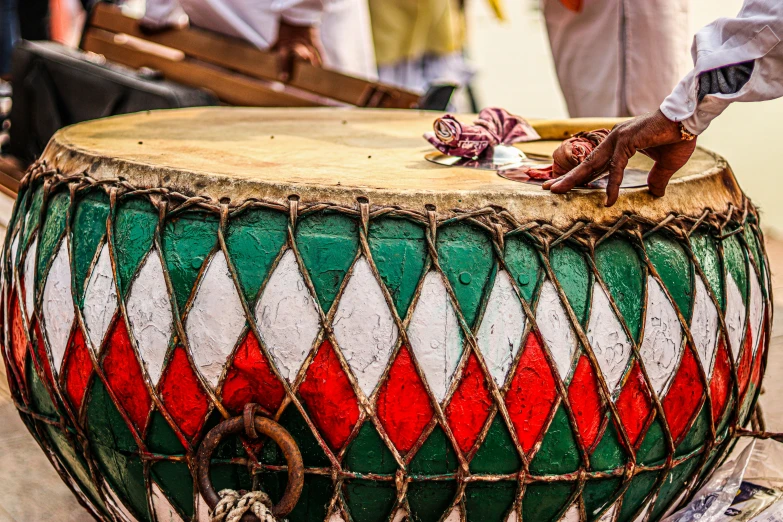 a man that is standing next to a drum, by Julia Pishtar, pexels contest winner, hurufiyya, green and red, thumbnail, hindu ornaments, preparing to fight