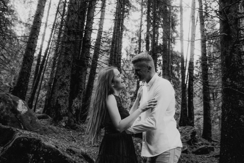 a man and woman standing next to each other in a forest, a black and white photo, by Emma Andijewska, pexels contest winner, 15081959 21121991 01012000 4k, cutest, in mountains, smiling at each other