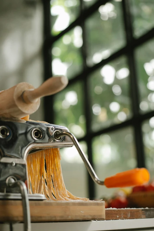 a pasta maker sitting on top of a wooden cutting board, a picture, levers, afternoon, master pieces, up close