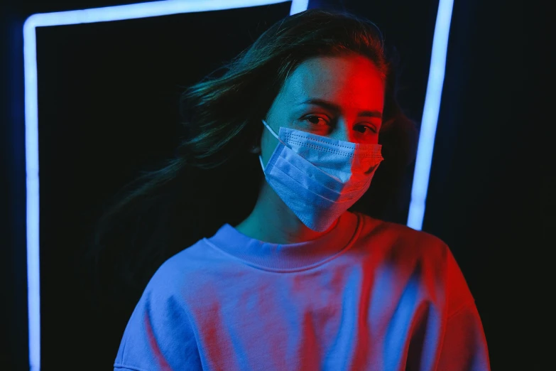 a woman wearing a face mask in front of a neon frame, pexels contest winner, antipodeans, blue and red tones, medical, teenage girl, medicine