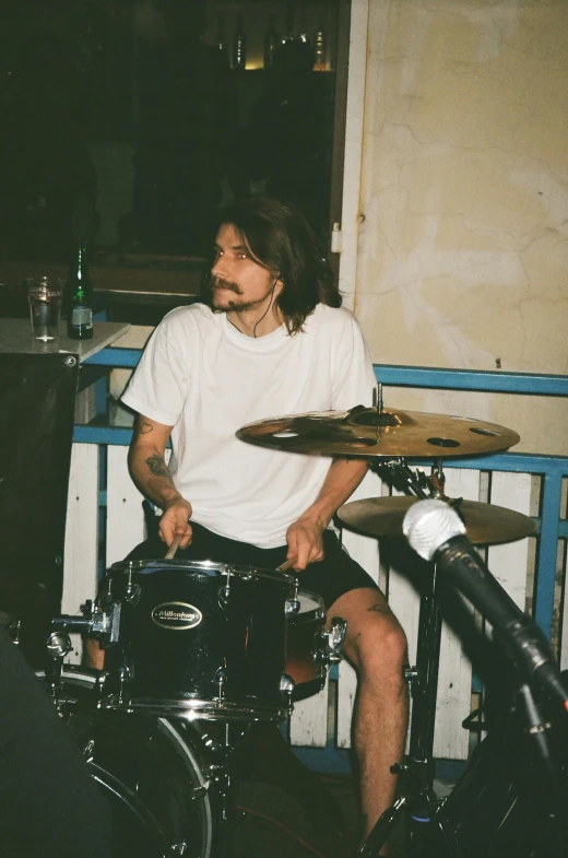 a man sitting on top of a drum kit, mark edward fischbach, profile image, mid long hair, slightly smirking