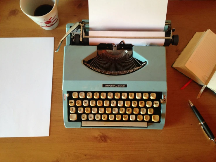 a typewriter sitting on top of a wooden table next to a cup of coffee, teal paper, multiple stories, image