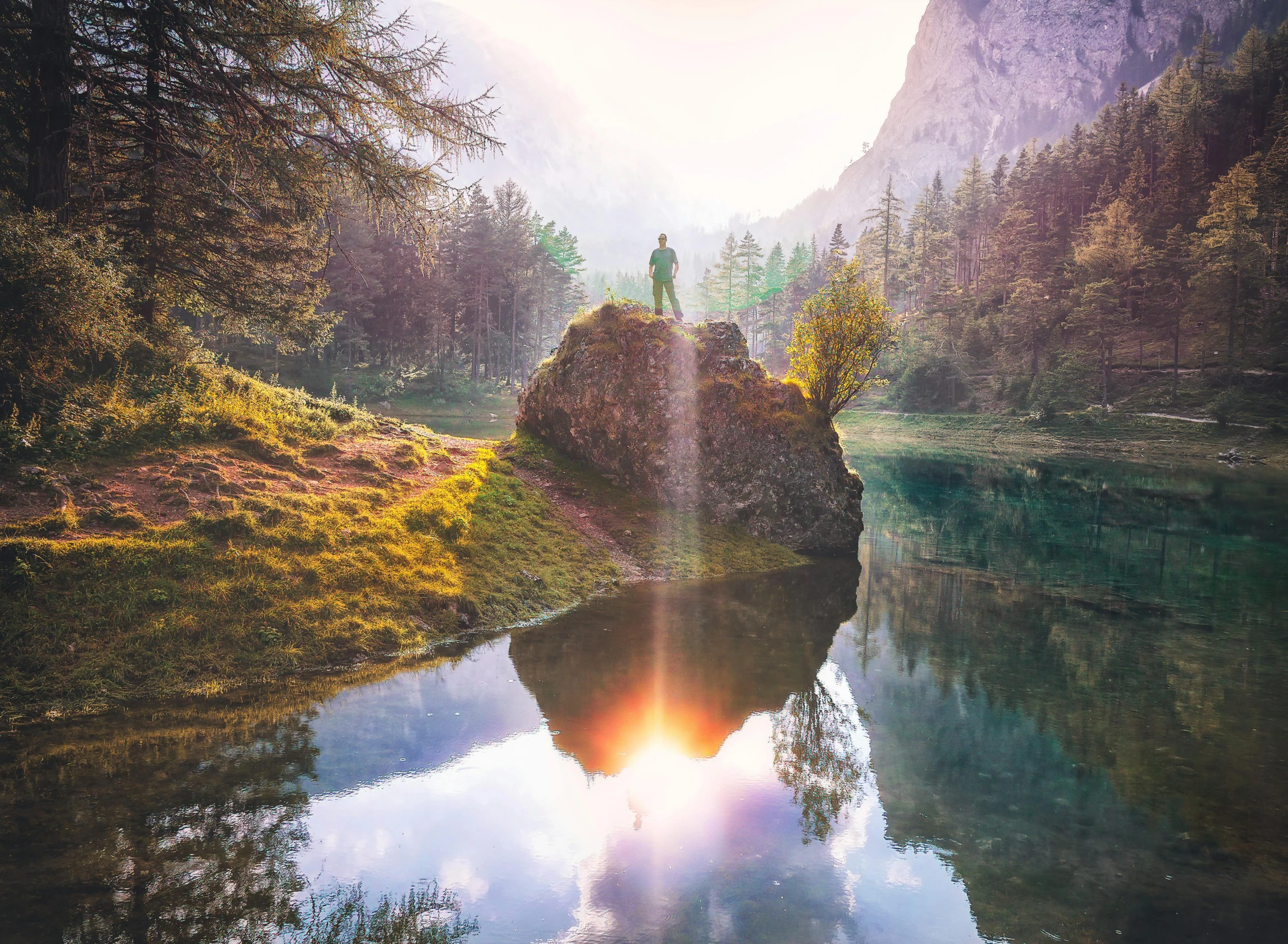 a man standing on top of a rock next to a lake, by Sebastian Spreng, pexels contest winner, romanticism, water reflecting suns light, mountains river trees, symmetrical fantasy landscape, sunflare