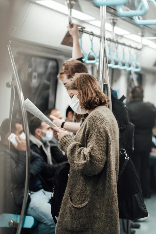 a woman wearing a face mask on a subway train, pexels contest winner, happening, trying to read, small crowd of people, 🚿🗝📝, a handsome