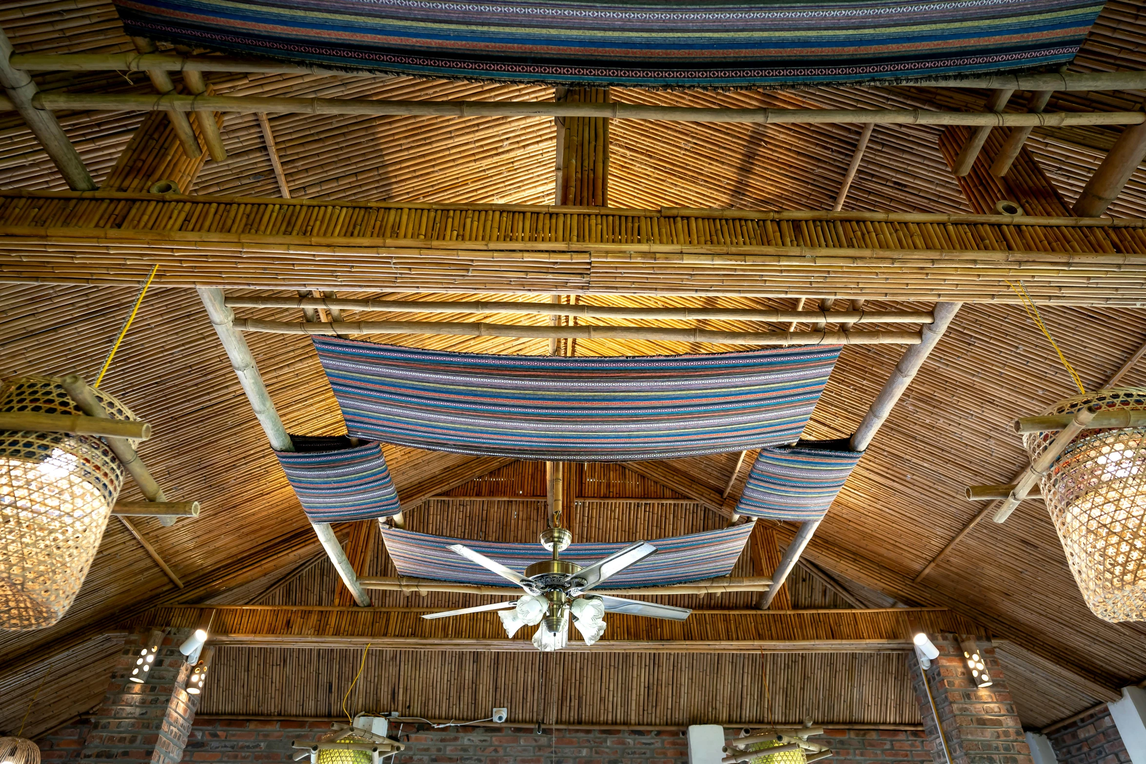 a living room filled with furniture and a ceiling fan, by Jan Tengnagel, unsplash, kinetic art, thatched roofs, awnings, hanging cables, the poolrooms