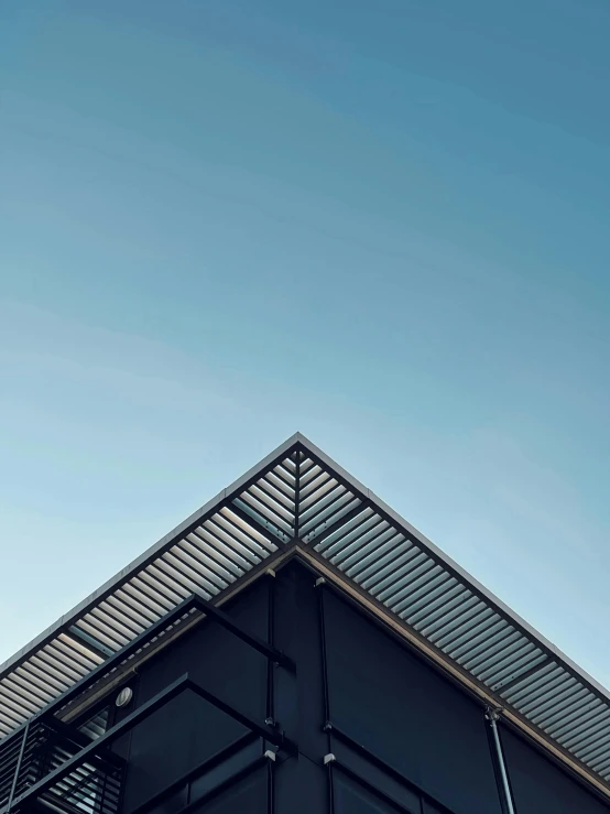 a black building with a blue sky in the background, a photo, pexels contest winner, minimalism, galvalume metal roofing, square lines, ilustration, soft grey and blue natural light