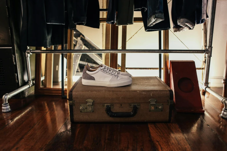 a suit case sitting on top of a wooden floor, by Raphaël Collin, pexels contest winner, renaissance, wearing white sneakers, sitting on a store shelf, leather and suede, white and grey