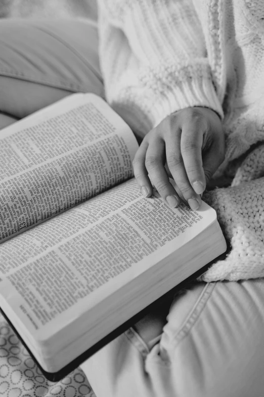 a person sitting on a bed reading a book, a black and white photo, by Nathalie Rattner, pexels, christianity, words, 15081959 21121991 01012000 4k