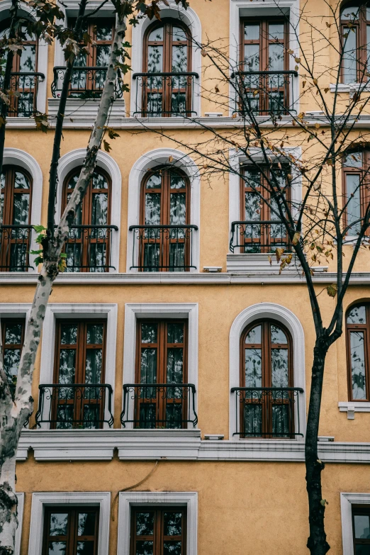 a tall yellow building with many windows and balconies, inspired by Germán Londoño, pexels contest winner, art nouveau, tlaquepaque, black windows, gif, square