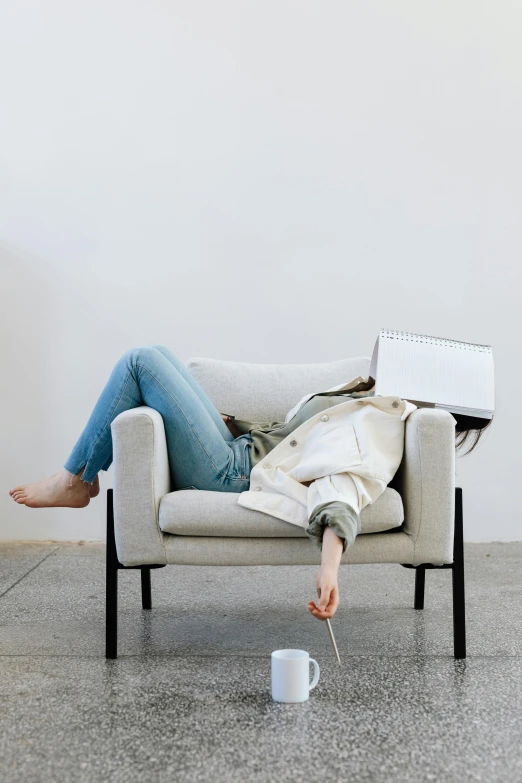 a woman sitting in a chair with a laptop on her lap, inspired by Sarah Lucas, trending on unsplash, happening, wearing a white sweater, sprawled out, denim, minimalist furniture