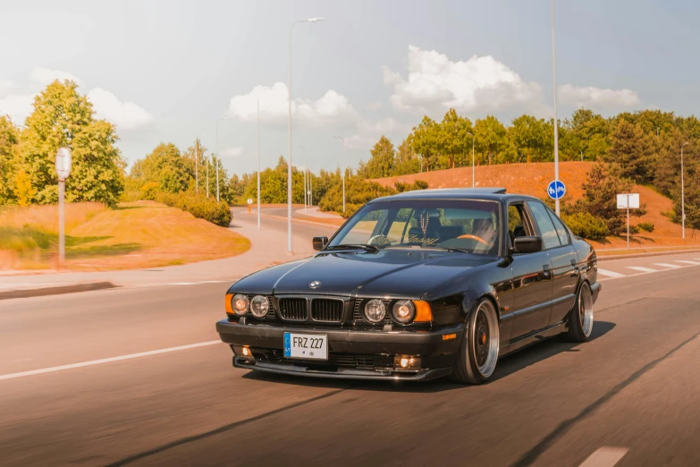 a black car is driving down the road, a portrait, by Jan Tengnagel, unsplash, baroque, bmw, restomod, 90's photo, sweden